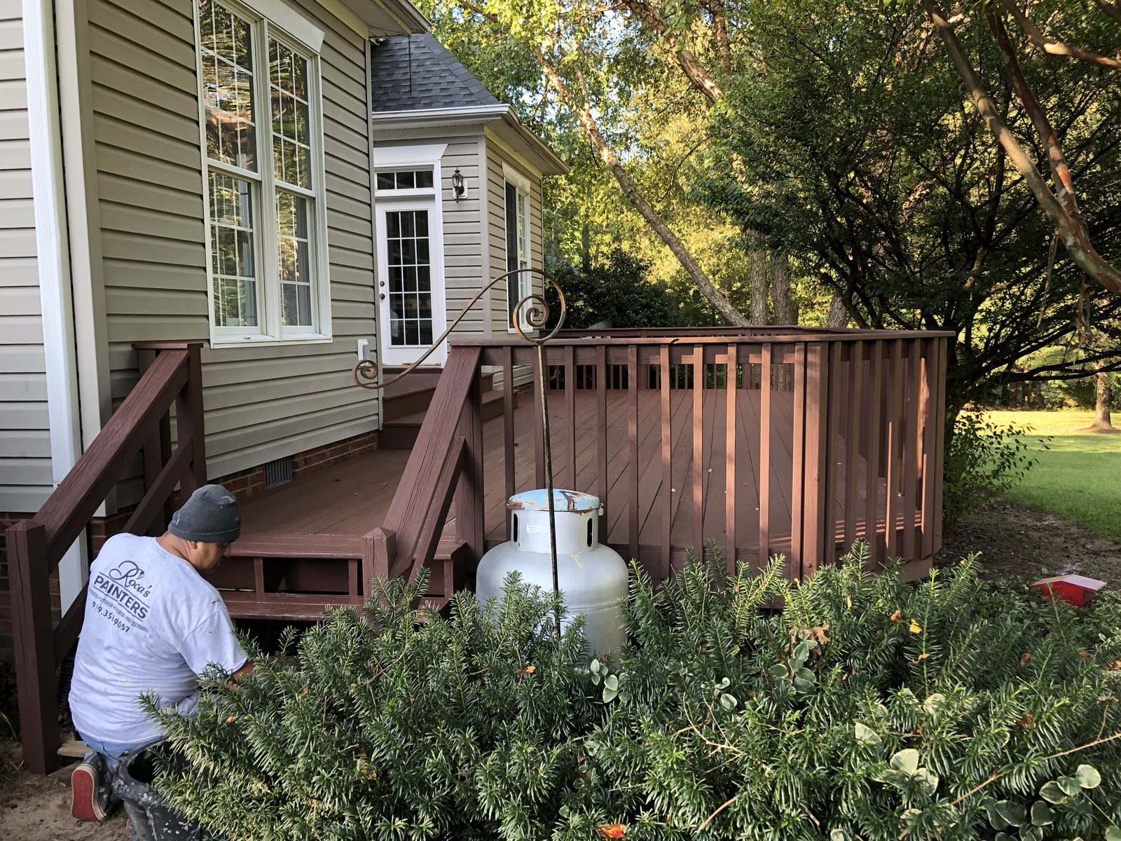 Painter applying stain to a backyard deck
