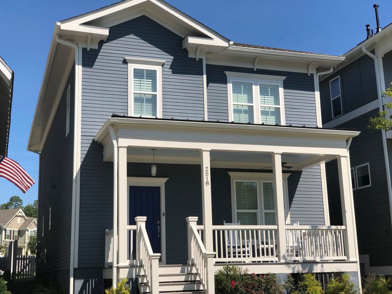 Navy two-story home with white trim and covered front porch painted
