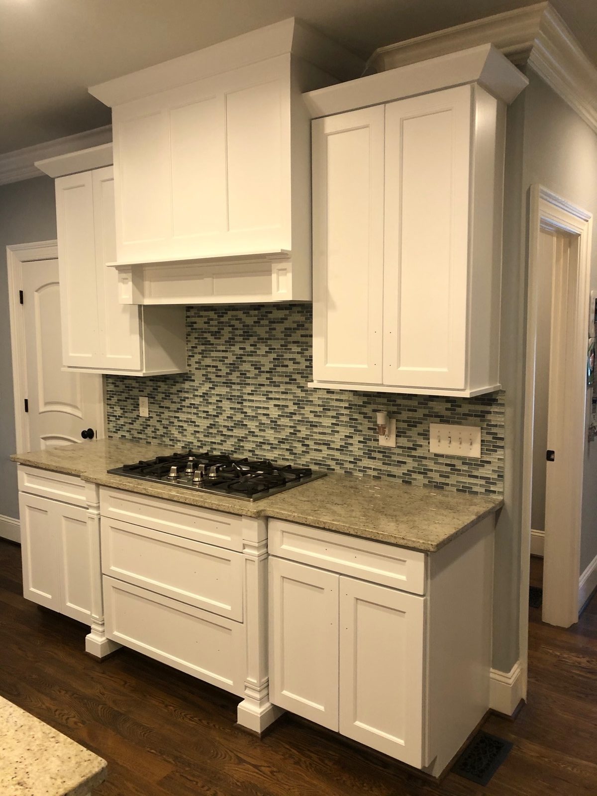 Range hood surround and upper cabinets painted white with a factory-smooth finish