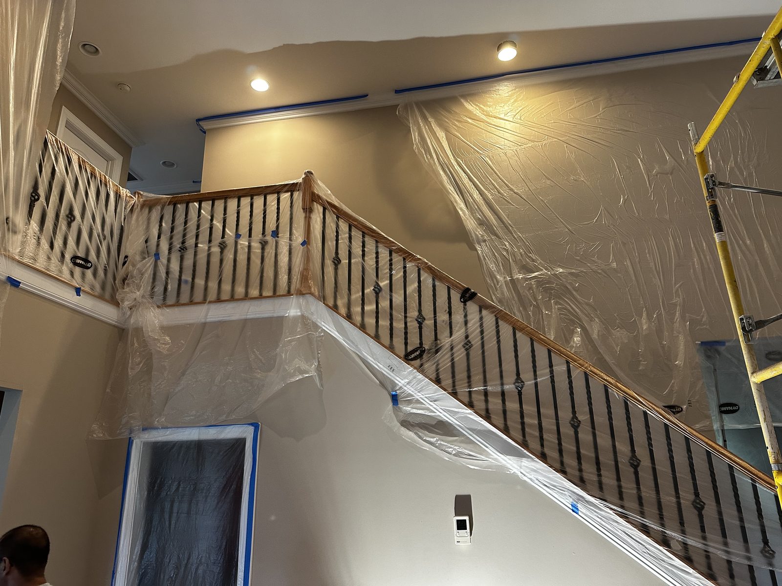 Stairwell railings and floors masked with plastic before interior painting begins