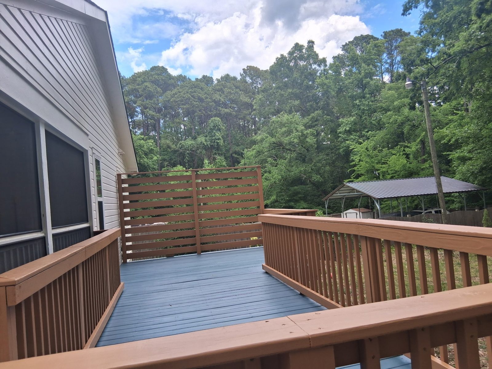 Deck with gray painted floor and tan railings with a privacy screen