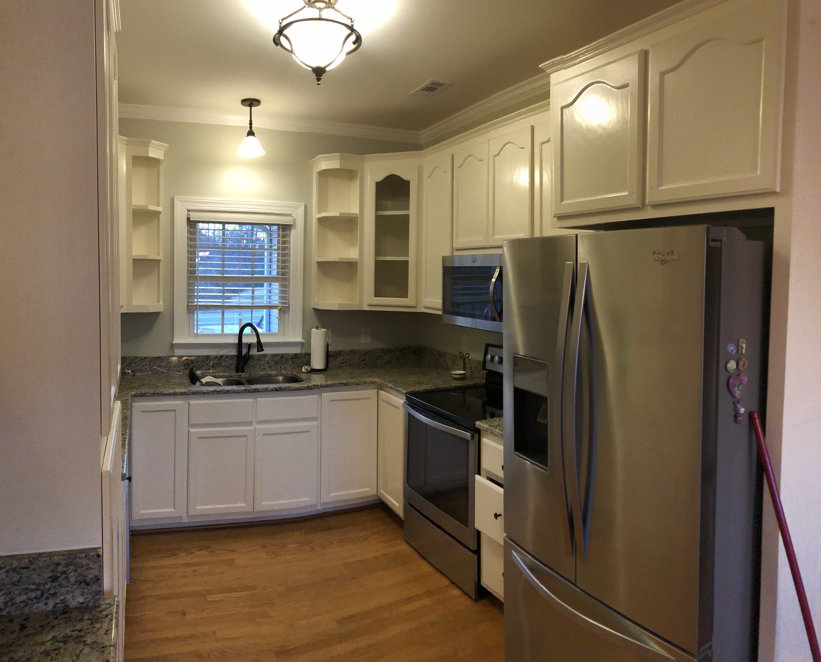 Small kitchen with arched cabinet doors refinished in a soft white