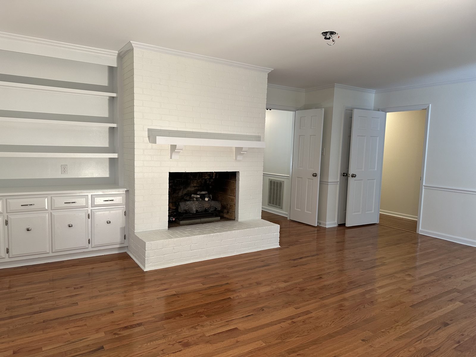 Painted white brick fireplace with built-in shelves and cabinets