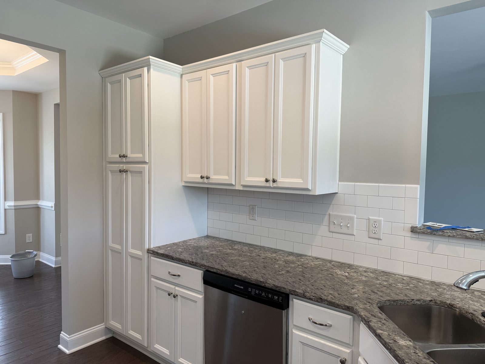 Upper cabinets and pantry column refinished in a satin white over raised-panel doors