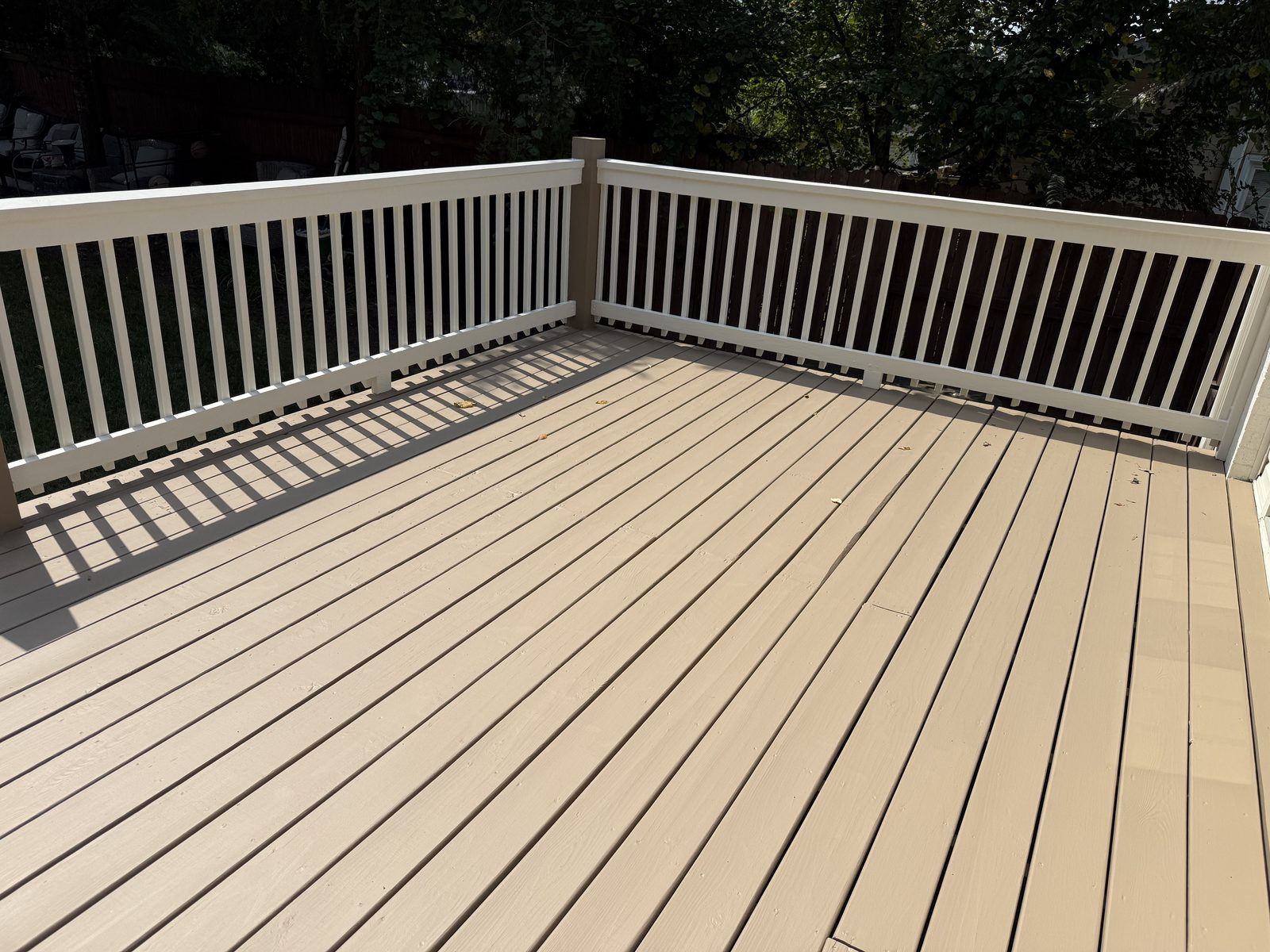 Corner of a tan deck with white painted balusters