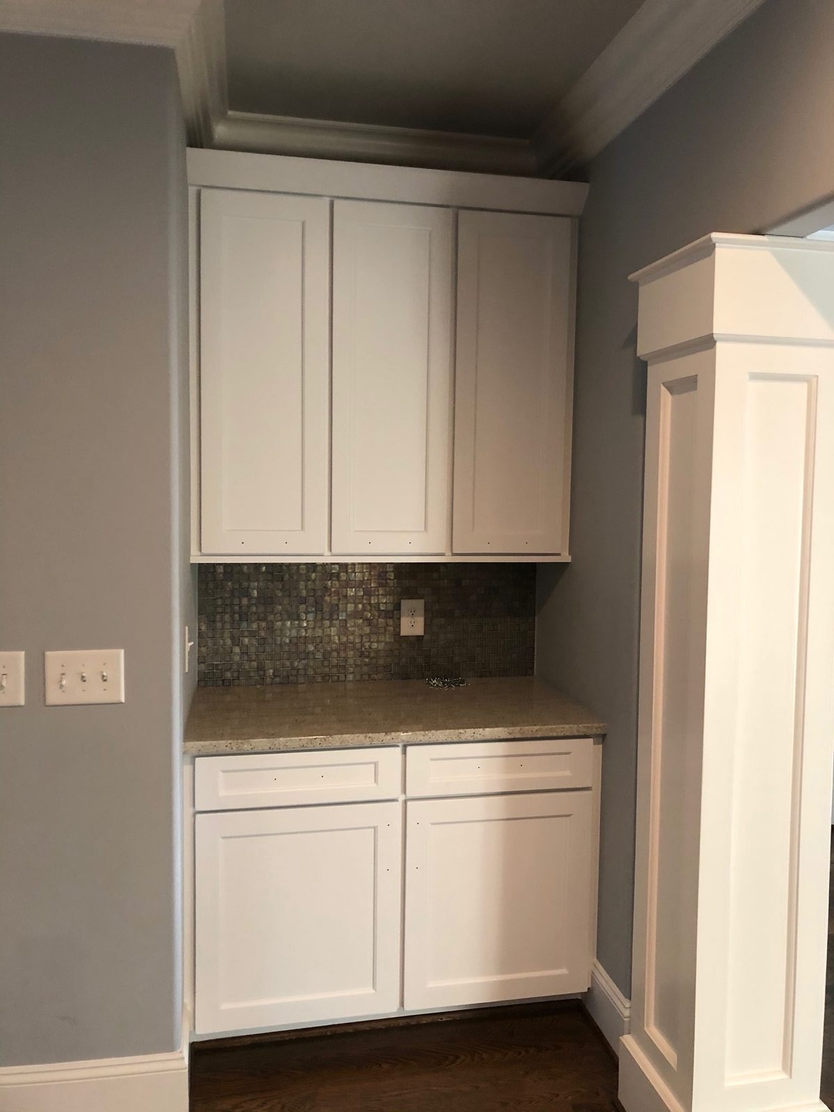 Butler's pantry cabinets painted white against a glass mosaic backsplash