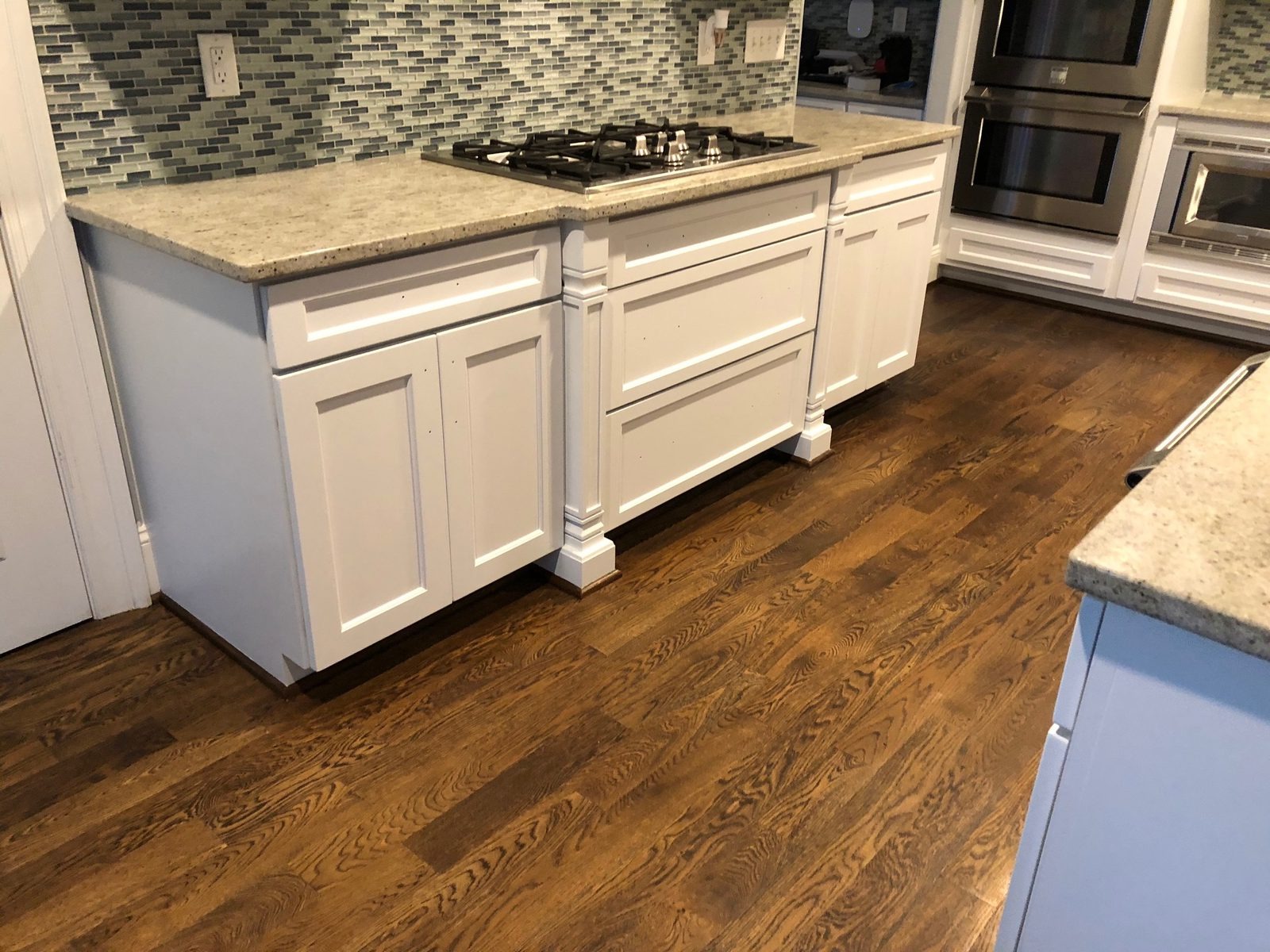 Island and base cabinets sprayed white with crisp panel edges and turned legs