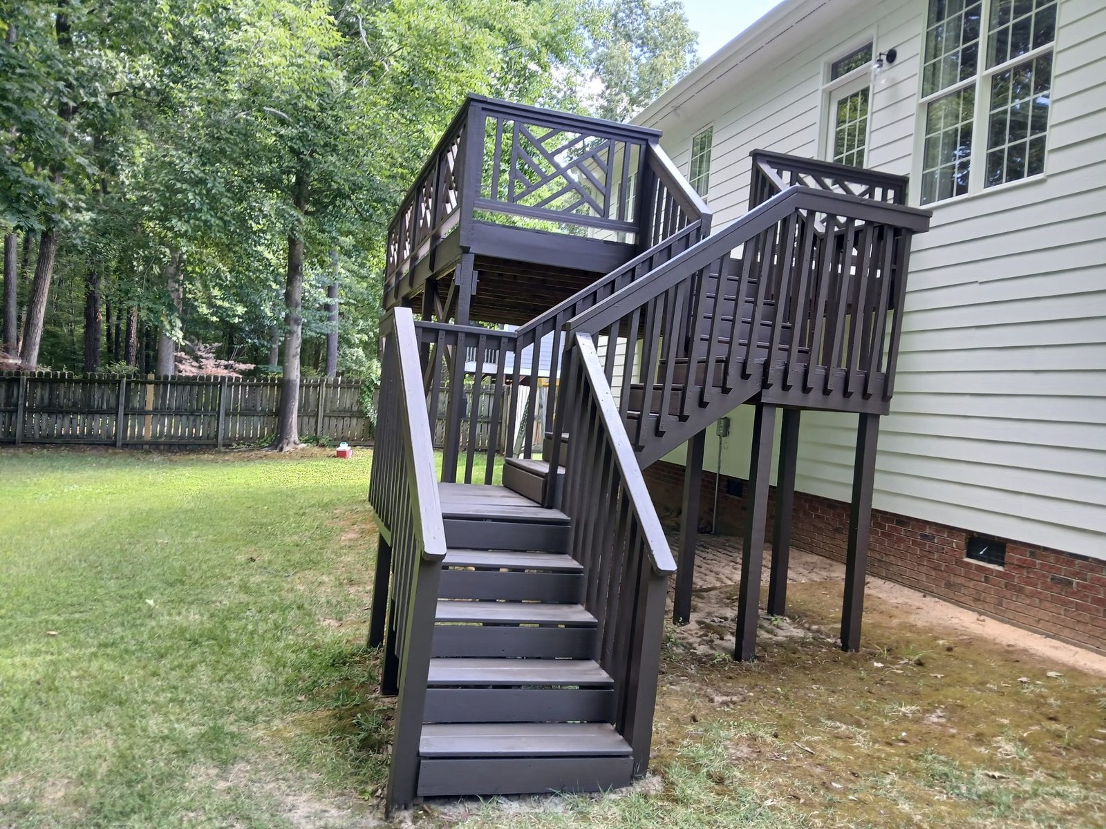 Deck stairs and railings stained dark against white siding