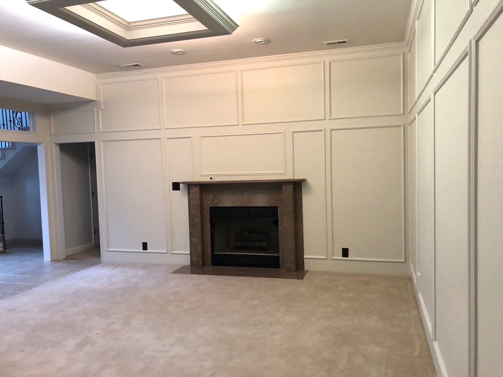 Living room with white picture-frame wall paneling painted around a fireplace